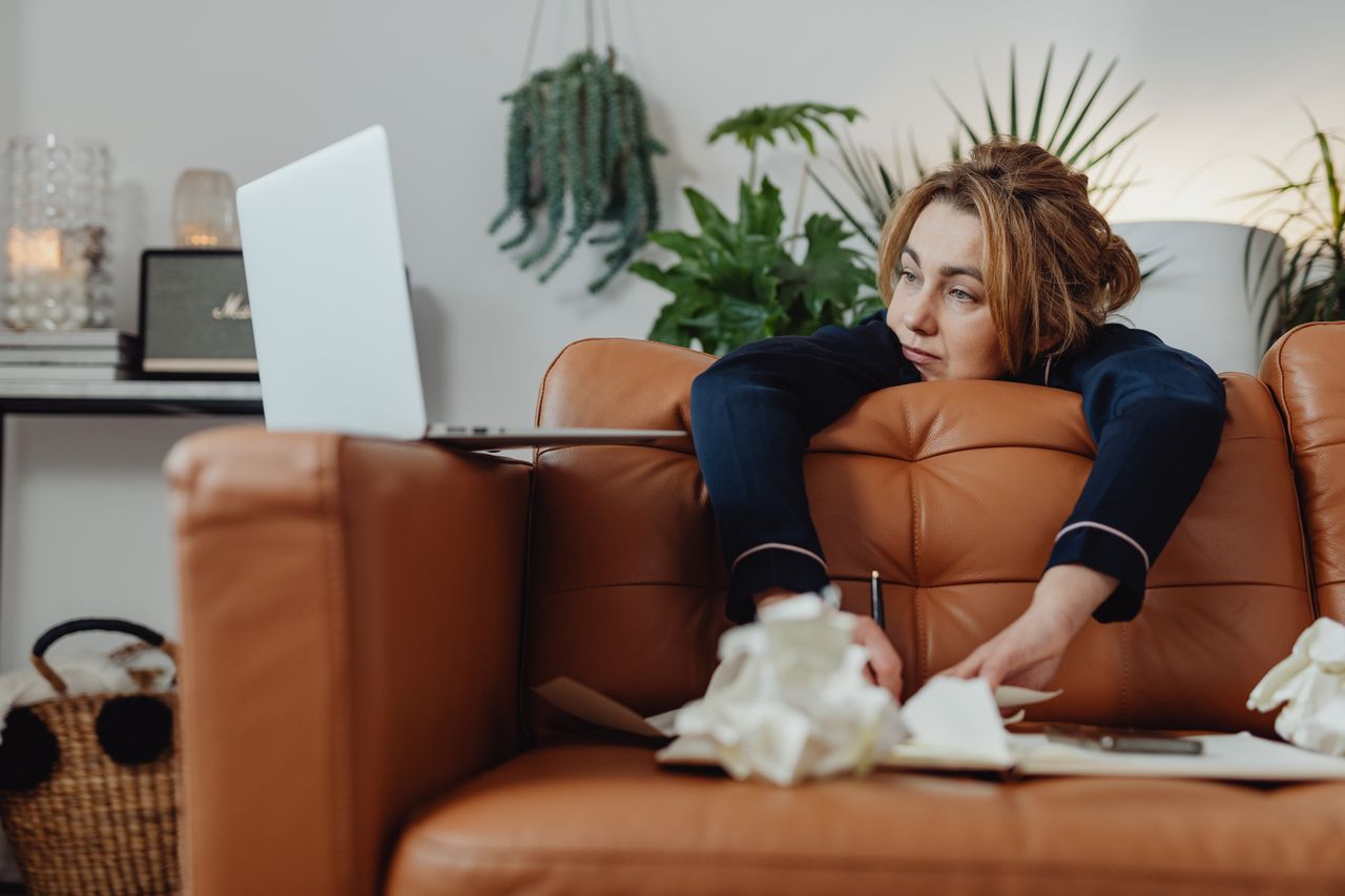 Woman on a sofa looking stressed and anxious while working