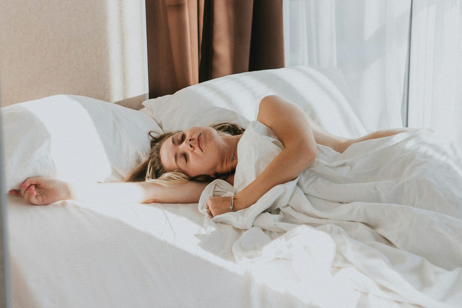 Woman resting peacefully in bed with soft natural light, representing fatigue and low energy