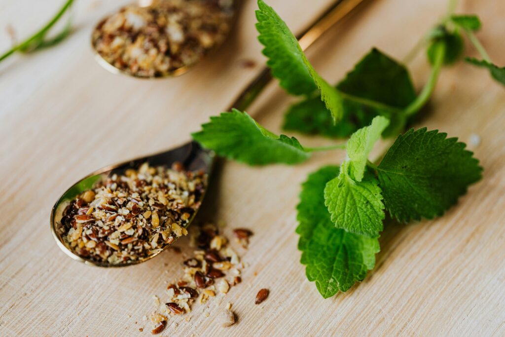Herbal seeds and fresh green leaves on wooden surface for natural health support