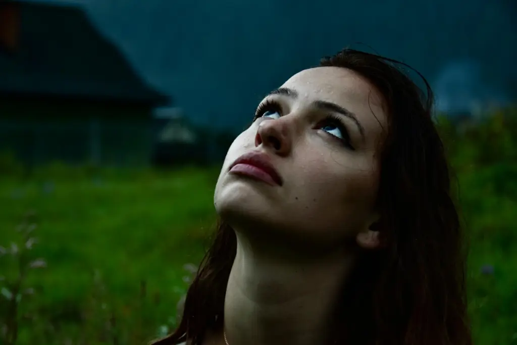 Woman looking up outdoors in low light, representing stress and sleep disruption as a trigger for jawline breakouts